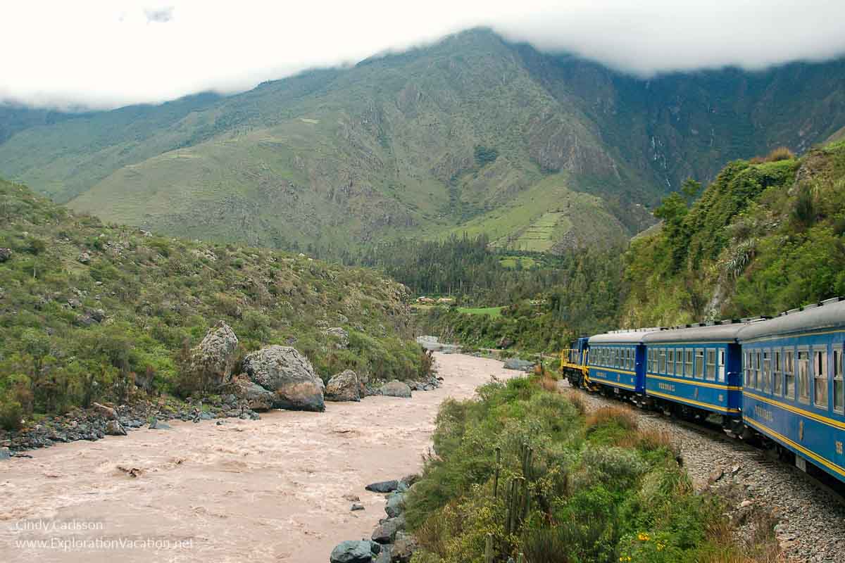 passenger train along a river through the mountains