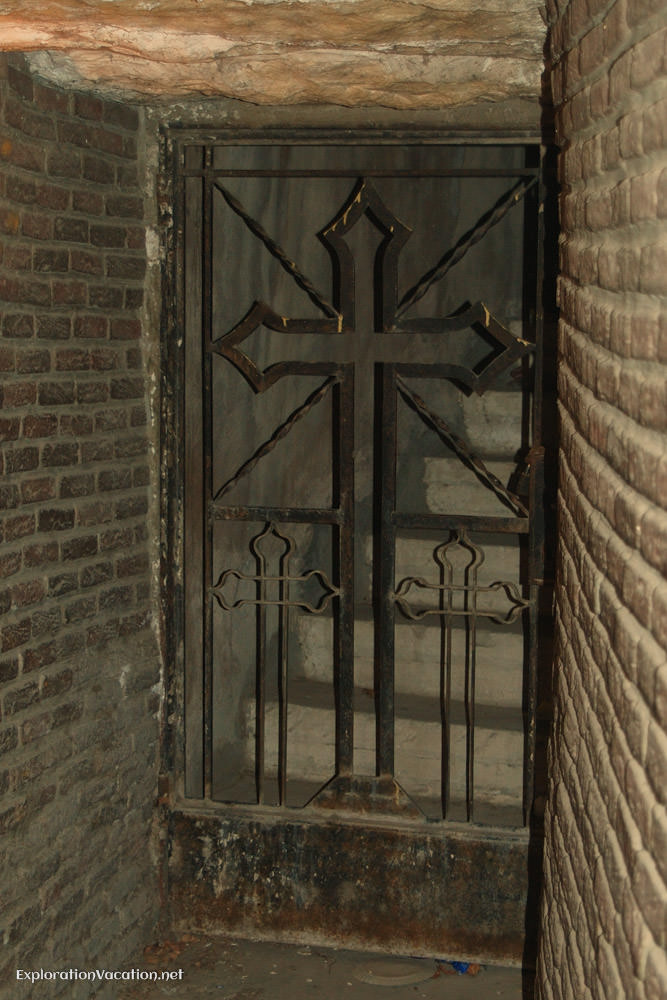 Metal gate with a cross blocking a stairway in a church basement.