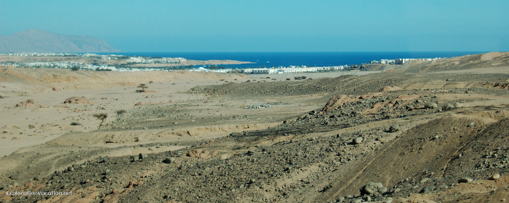 vacant land with buildings and sea in the distance