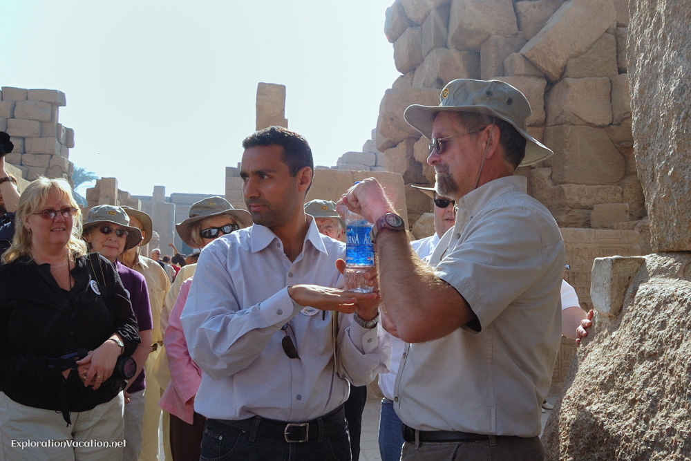 A tour guide using a water bottle to explain to a group how things were raised.