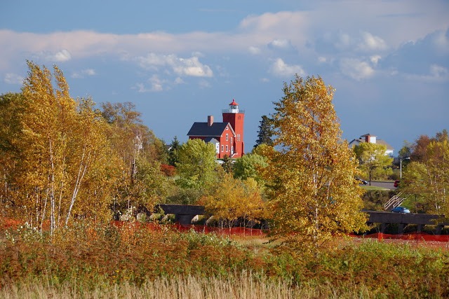 photo of the bright red brick Two Harbors lighthouse with fall foliage taken from a distance © Cindy Carlsson at ExplorationVacation.net