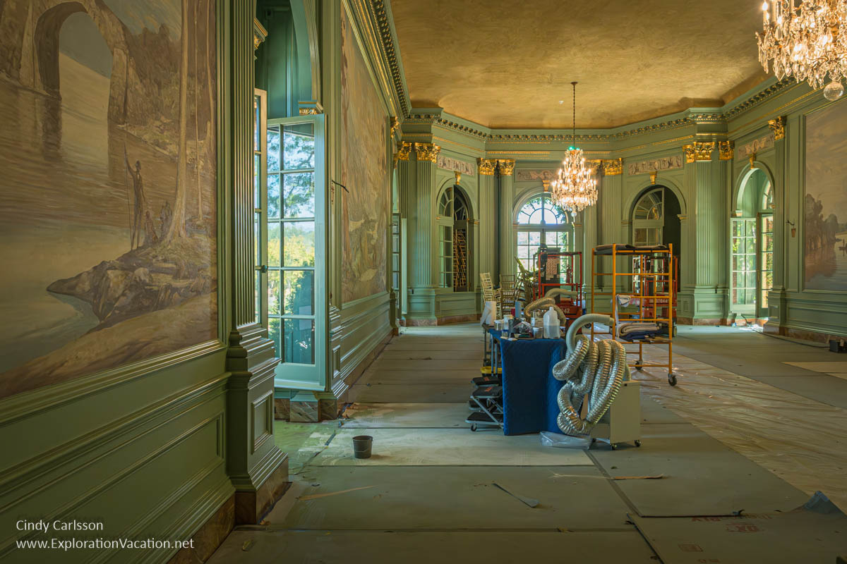 The ballroom with elaborate trim and chandelier and a vacuum and construction equipment during a 2024 renovation project.