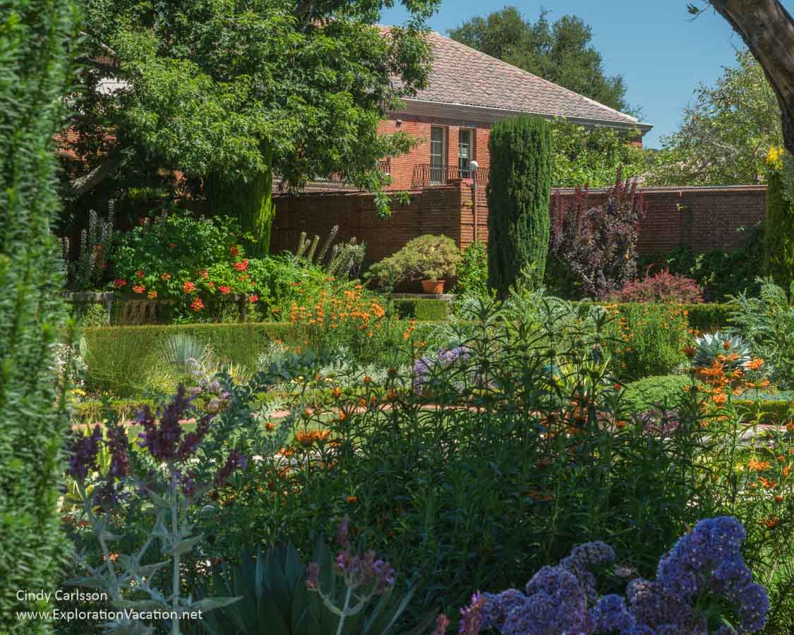 Portion of a garden with a large brick house (Filoli House) in the background. 