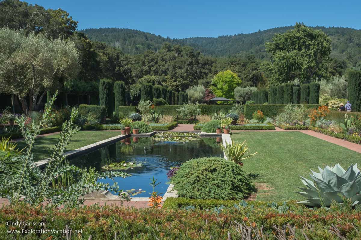 A lily pond with lawn and gardens and wooded hills in the distance.