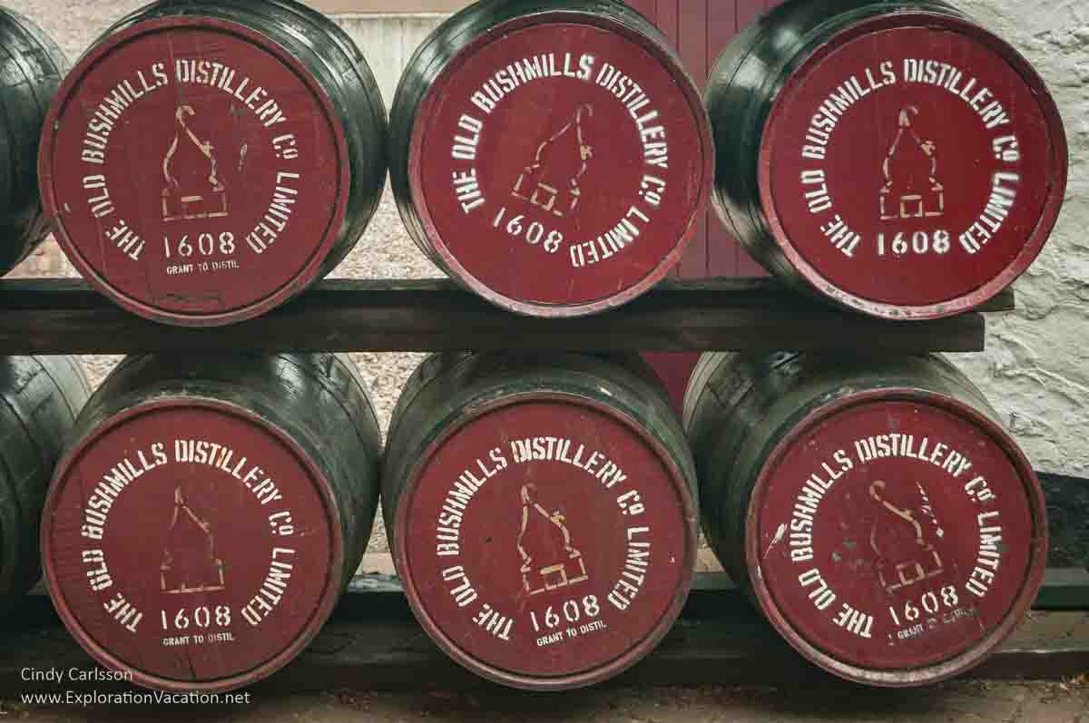 photo of barrels on a rack with ends painted to say "The Old Bushmills Distillery Co Limited 1608 in Northern Ireland &copy; Cindy Carlsson - ExplorationVacation.net