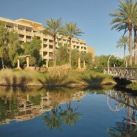 blue pools and palm trees behind the hotel