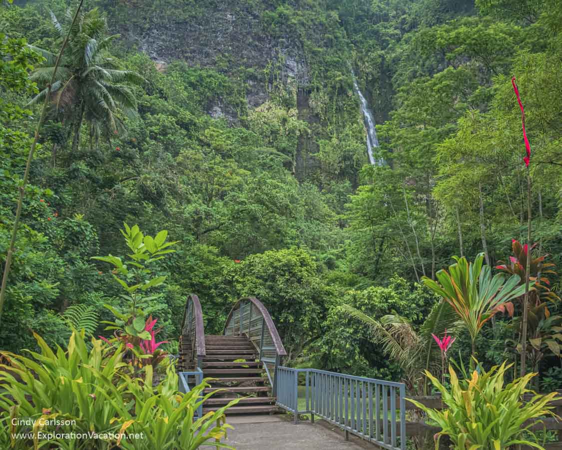 photo of a bridge and forest with Va'imahuta Waterfall in the background at the Fa'aruma'i waterfalls on Tahiti, French Polynesia &copy; Cindy Carlsson at ExplorationVacation