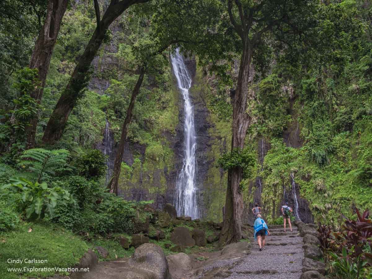 photo of a path through a forest with Va'imahuta Waterfall in the background at the Fa'aruma'i waterfalls on Tahiti, French Polynesia &copy; Cindy Carlsson at ExplorationVacation