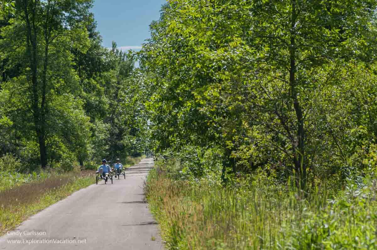 Recumbent bikes on a paved trail through a woods