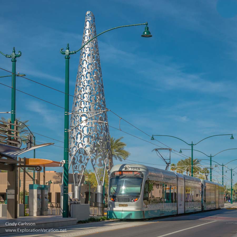 light rail train passing by a tall pine tree-shaped sculpture in Mesa Arizona