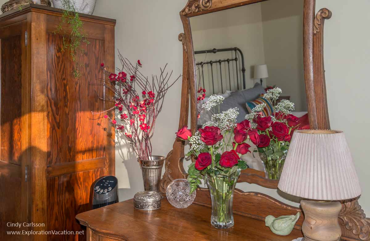 dresser with roses and mirror with reflection of bed