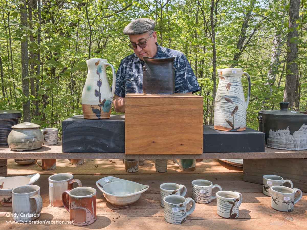 Photo of a man looking at pottery by Matthew Krousey during the 2024 St. Croix Valley Pottery Tour in Minnesota. (Photo &copy; Cindy Carlsson on ExplorationVacation.net)