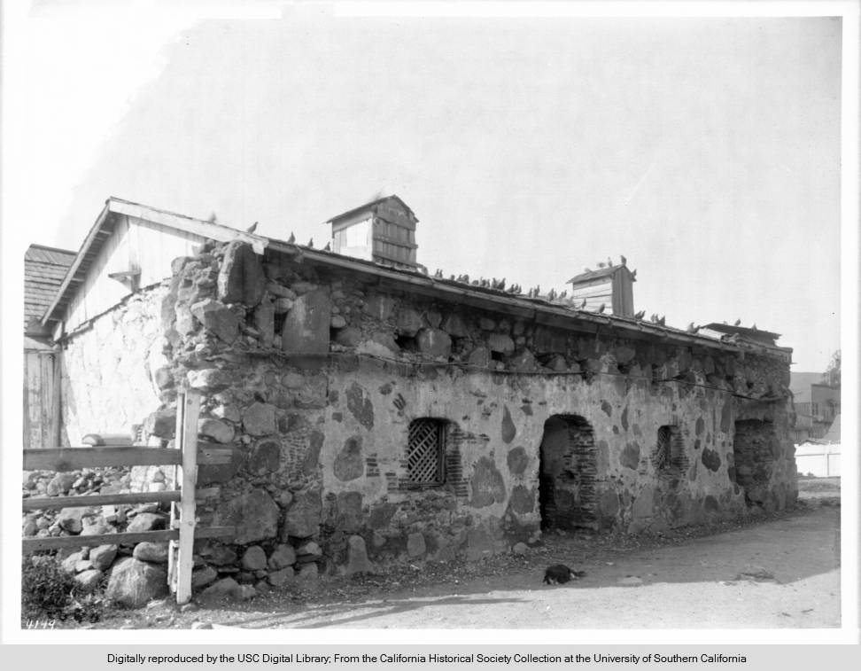 A_dog_sleeps_on_the_ground_in_front_of_the_Priests_residence_of_Mission_San_Luis_Obispo_de_Tolosa_ca1900