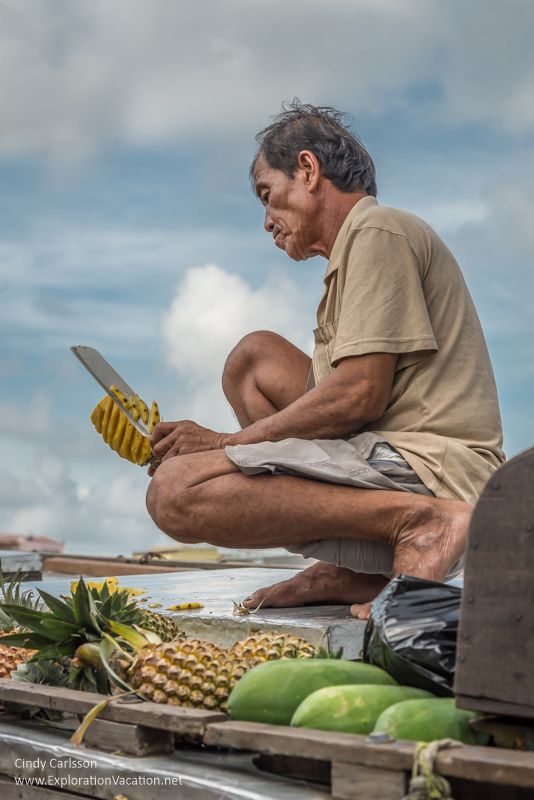 Man cutting pineapple at the Cai Rang floating market in the Mekong Delta Vietnam 