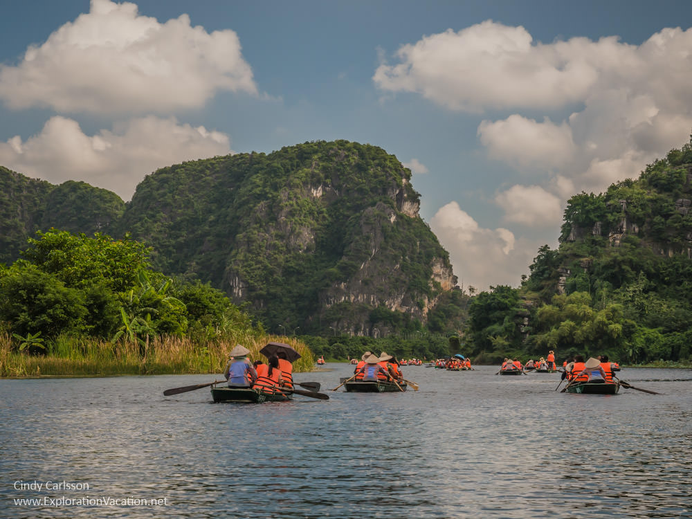 photo of small rowboats in a beautiful flooded valley between mountains in Trang An Vietnam - ExplorationVacation.net