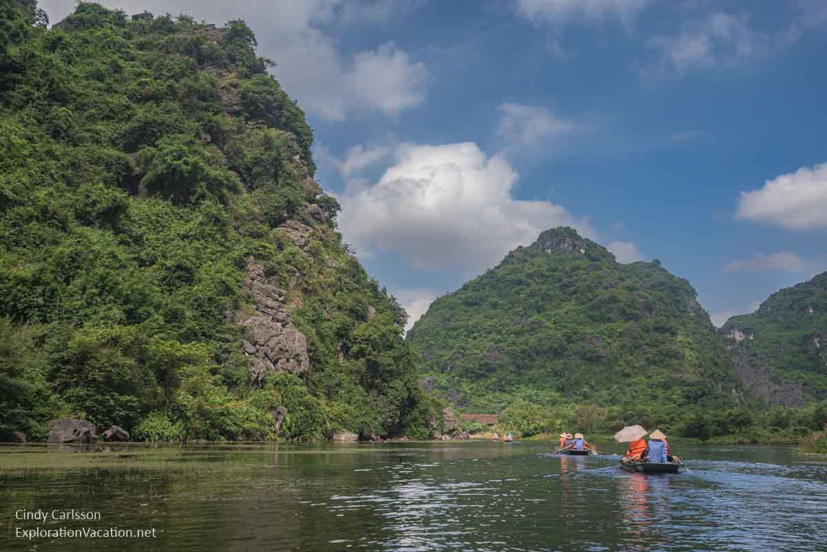 photo of small rowboats in a beautiful flooded valley between mountains in Trang An Vietnam - ExplorationVacation.net