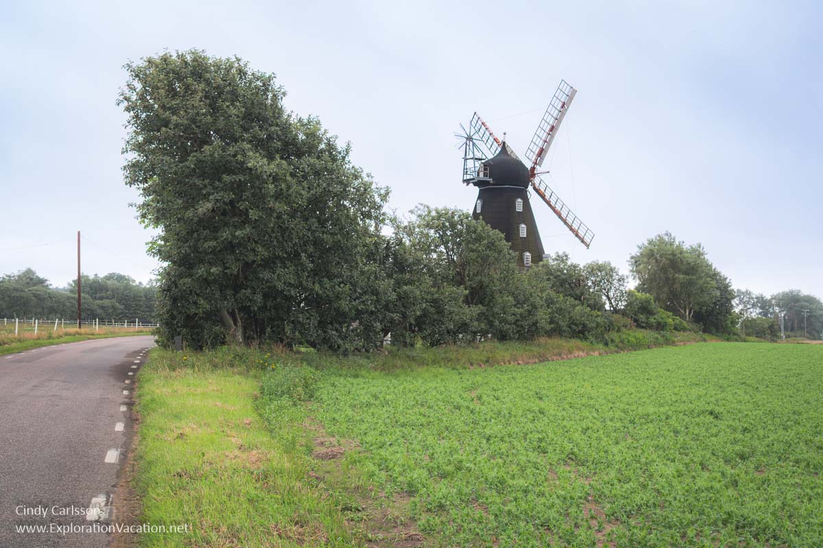 An old-fashioned windmill seen above the fields and trees.