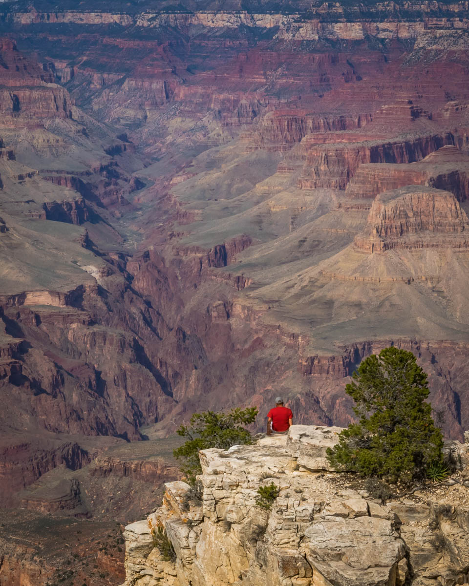 Man sitting on a rock above the Grand Canyon 