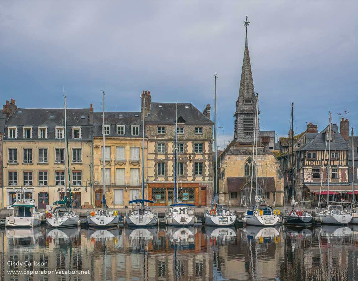 Sailboats in front of historic buildings along a small harbor