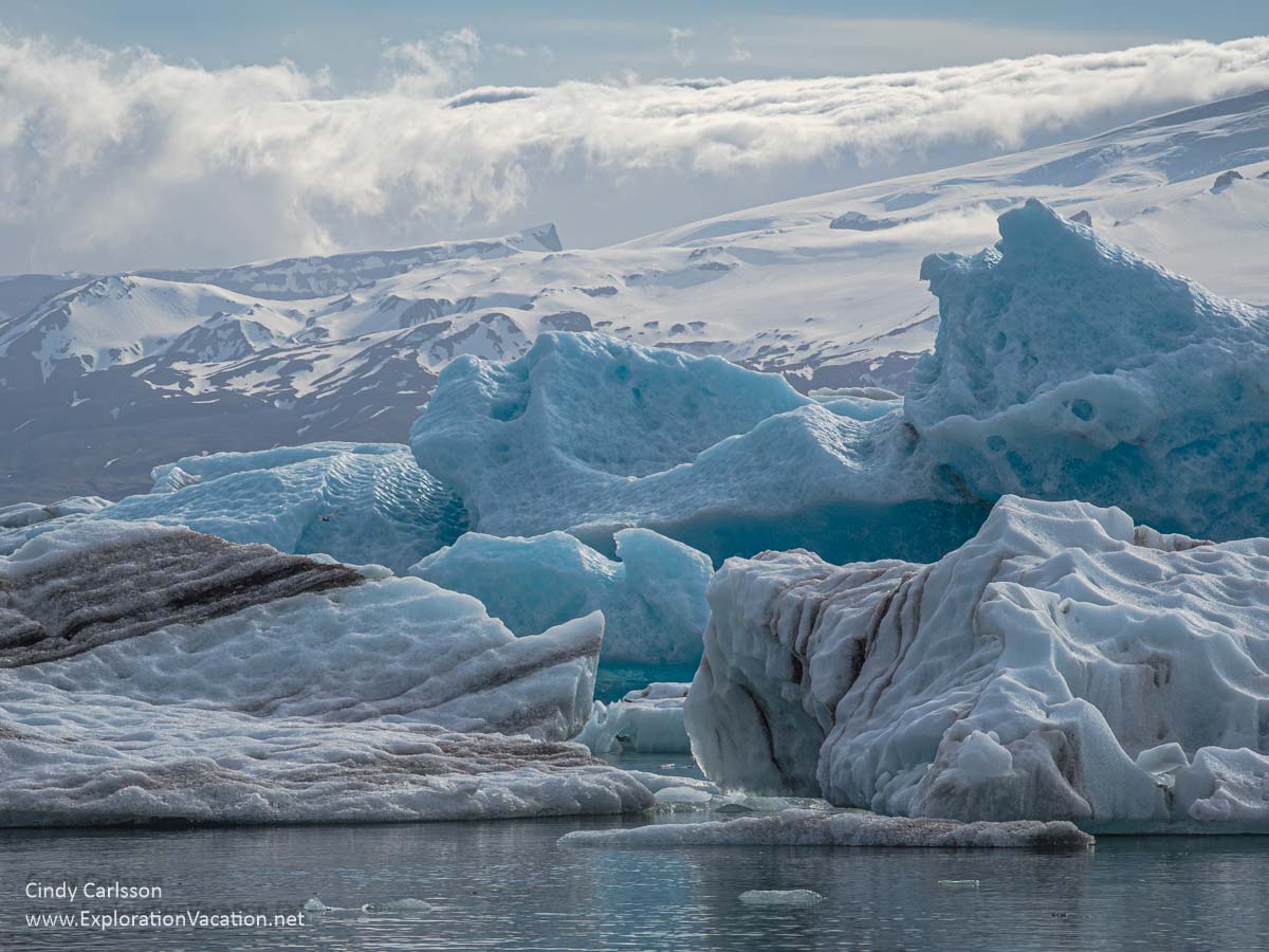 icebergs piled up in a lagoon with mountains in the background