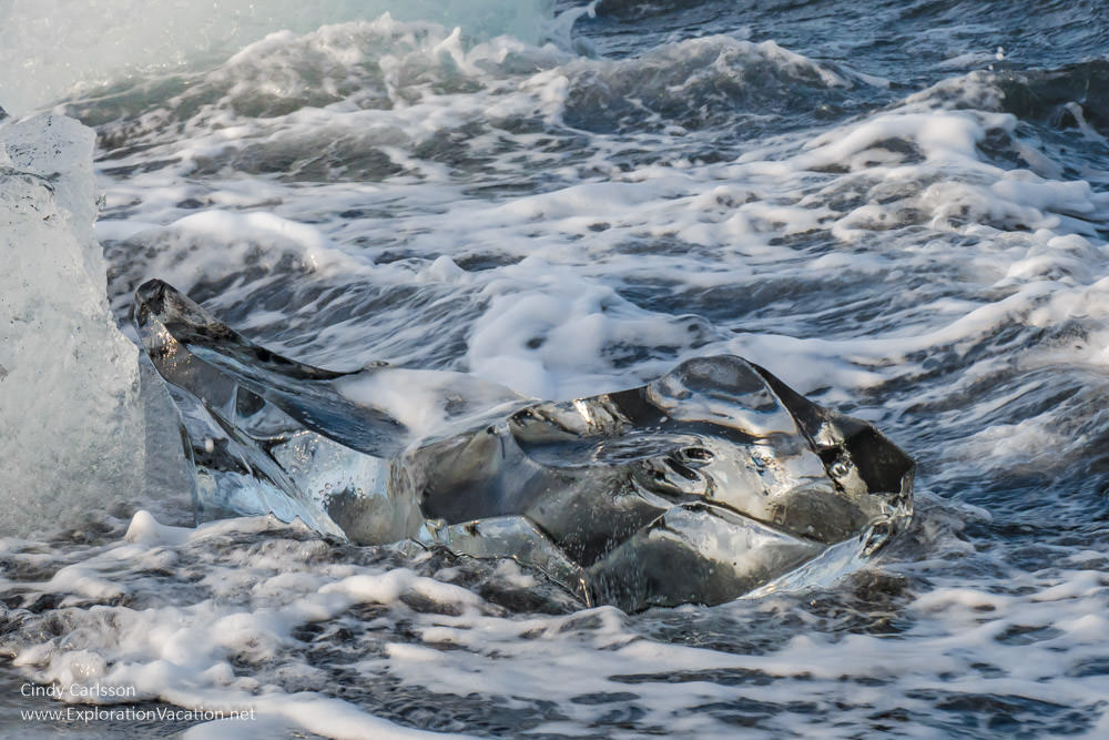 a chunk of glacial ice is washed by waves along Diamond beach