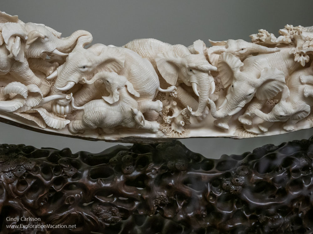 ivory carved with elephants on a carved wood base