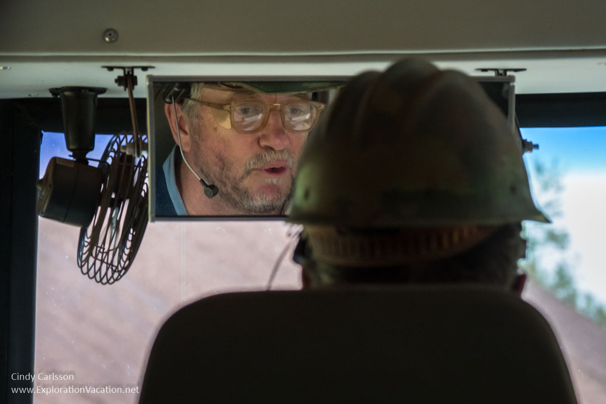 view of bus driver from behind with face visible in rear view mirror