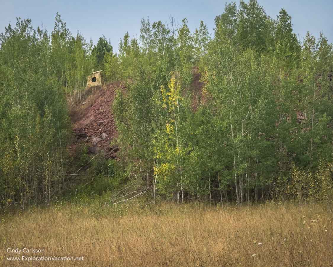 tailings pile surrounded by trees with a small building on top