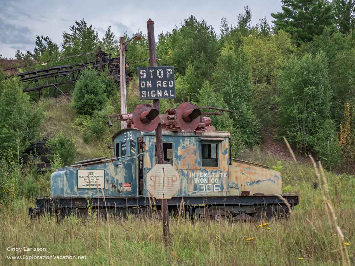 old rusty electric locomotive with a railroad sign and conveyor system 