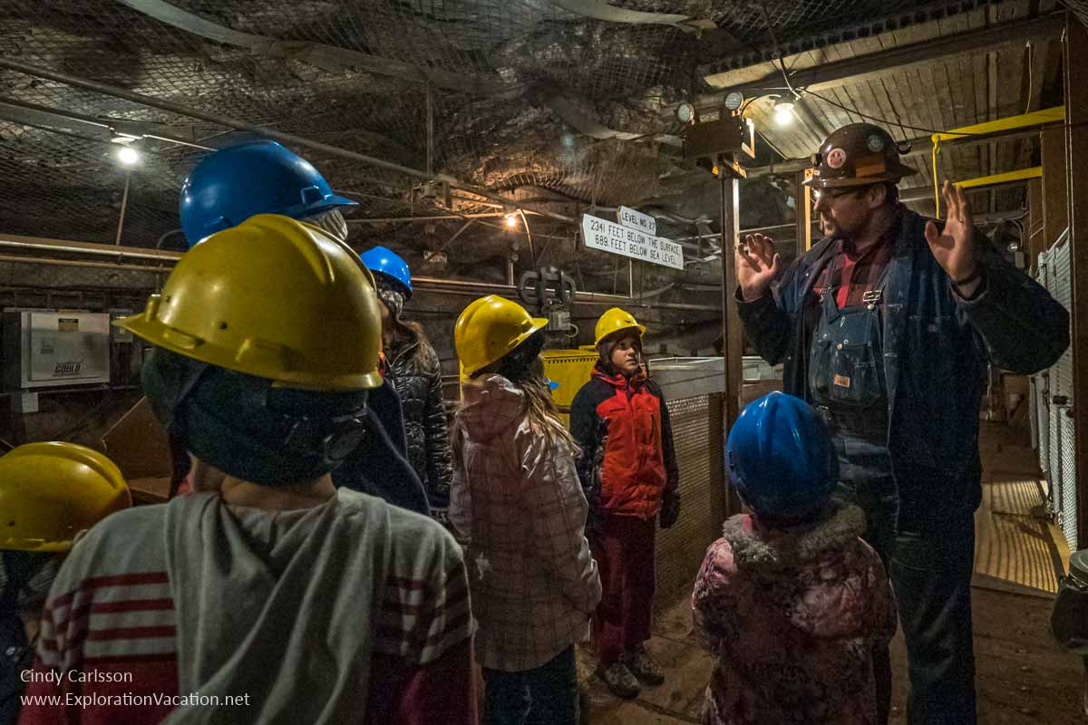 Man talking to a group of kids in hard hats in a mine