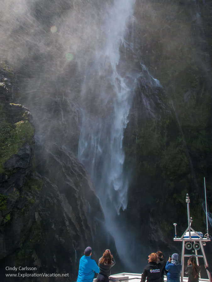 people on the upper deck of a ship as it approaches a waterfall