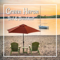sunset on a beach with chairs and umbrella and text "Green Heron B&B"
