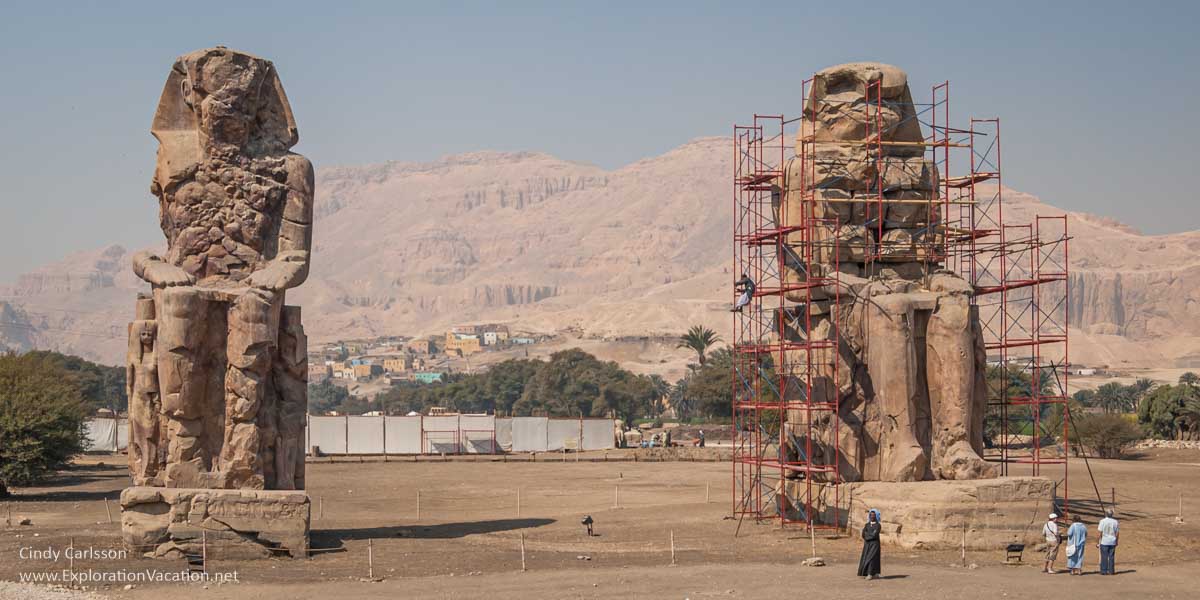 two enormous statues, one in scaffolding, on an empty plot
