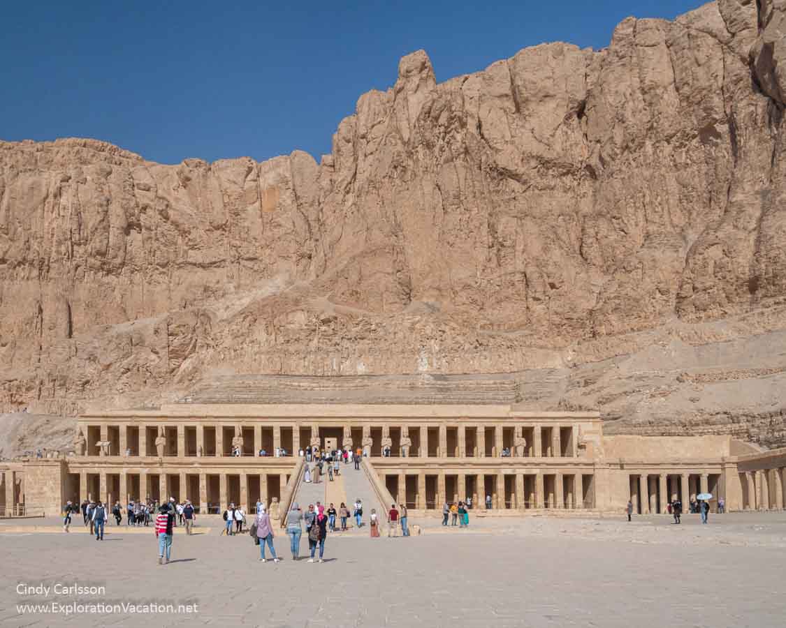 long two-story stone temple below a cliff