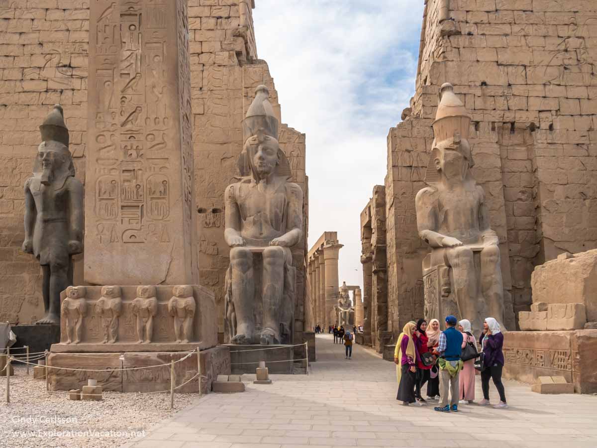 temple courtyard with huge statues, stone walls, and a group of tourists