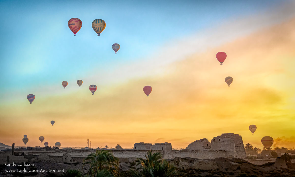 hot air balloons rise into the sky above the ruins of a temple at sunrise