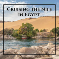 small boat tied to a tree with large dunes behind and text "Cruising the Nile in Egypt"