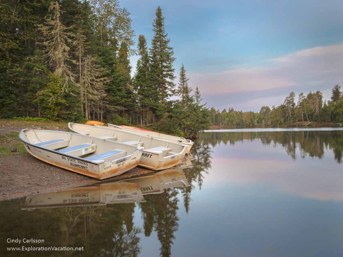 two small park boats on shore by a lake at sunset