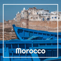 blue boats below a white city with text "Morocco"