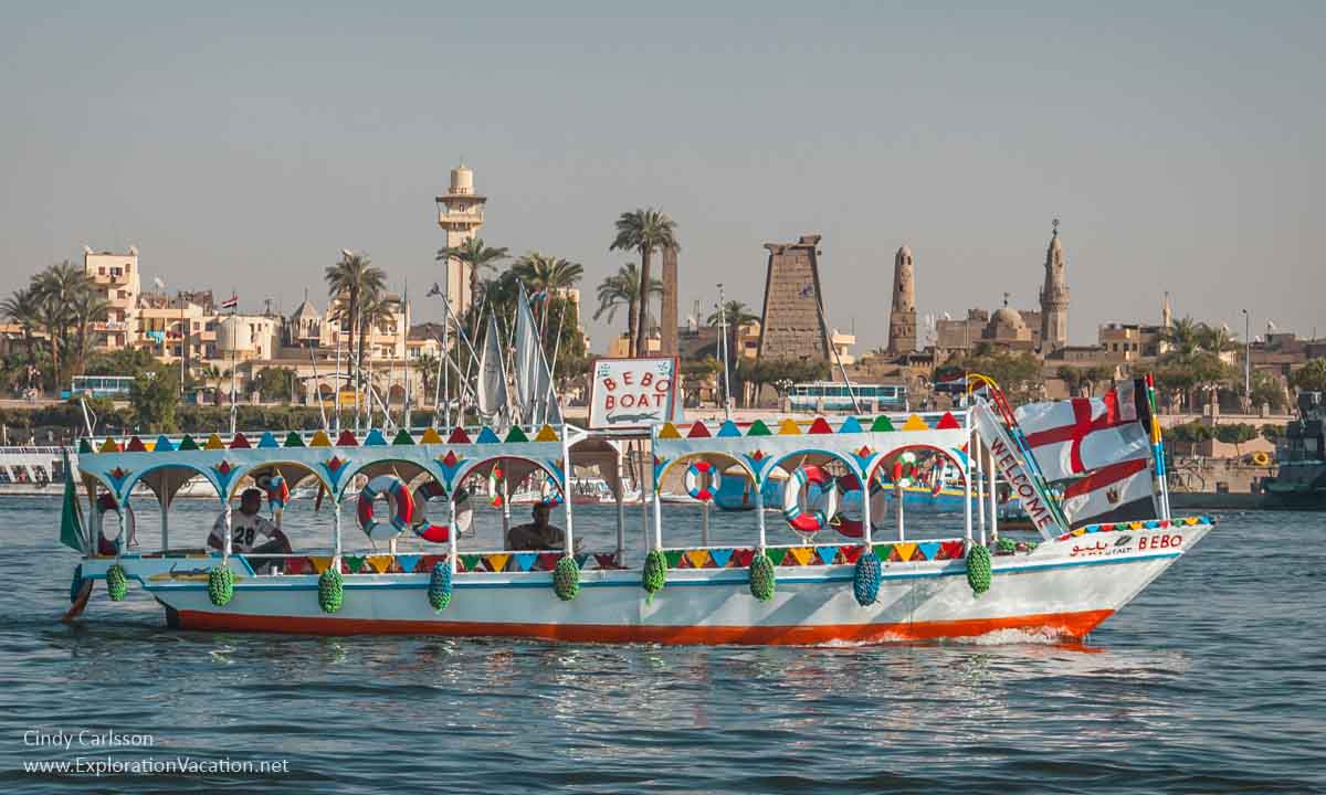 brightly colored small ferry with Luxor temple in background