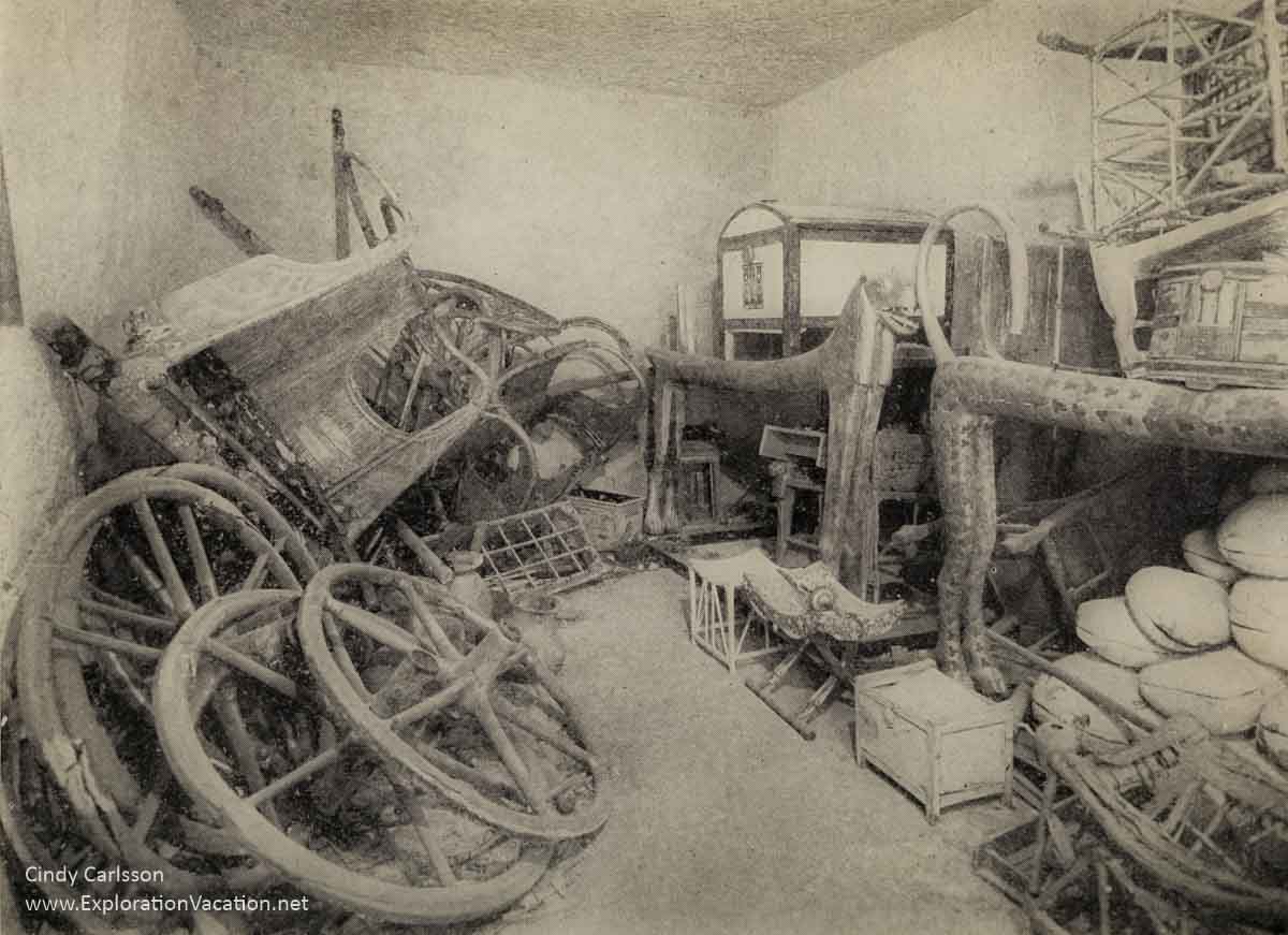 monochrome view of disassembled carriages and furniture in a plain room