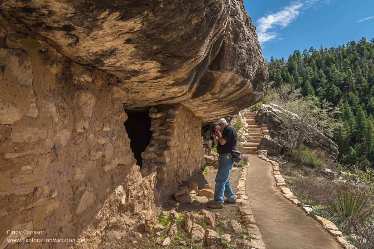 man taking a picture of the inside of a cliff dwelling 