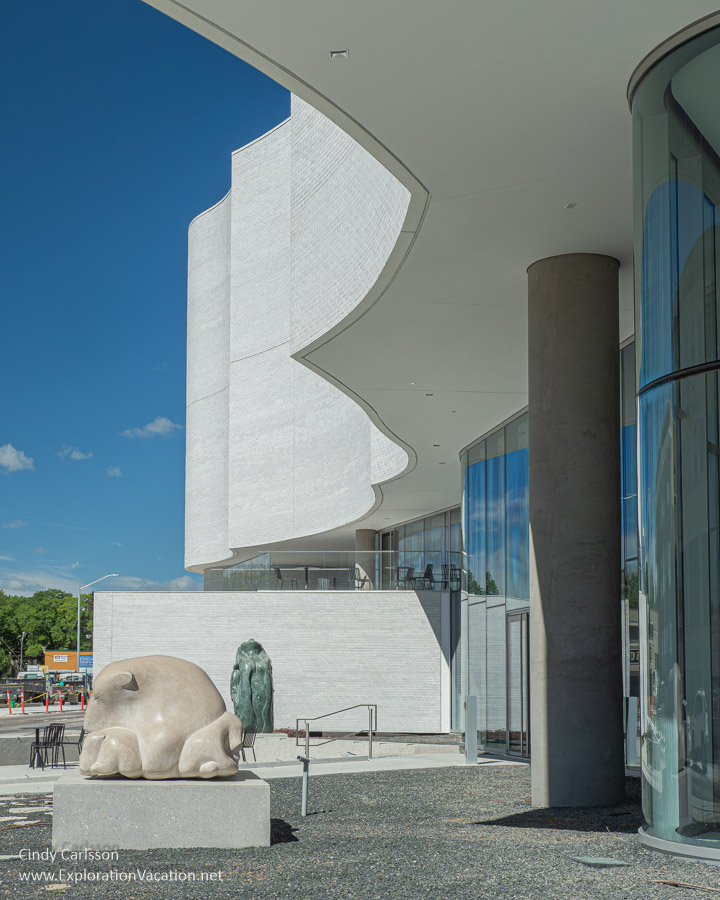 Front exterior with swooping white stone above and sculptures by the entrance.