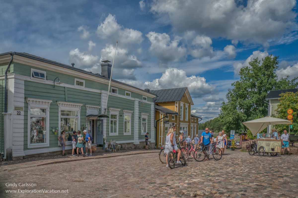 people in a square with historic wooden buildings in Finland