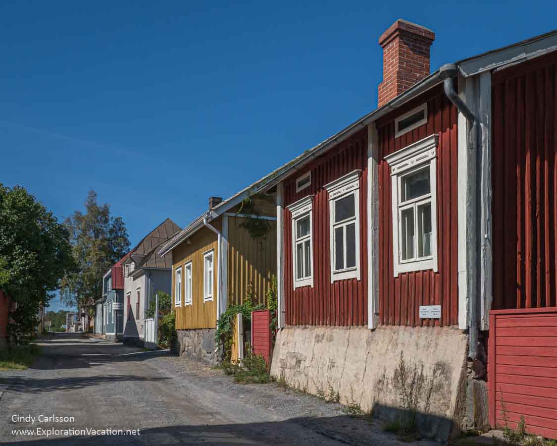 A row of brightly colored old wood houses along a street.