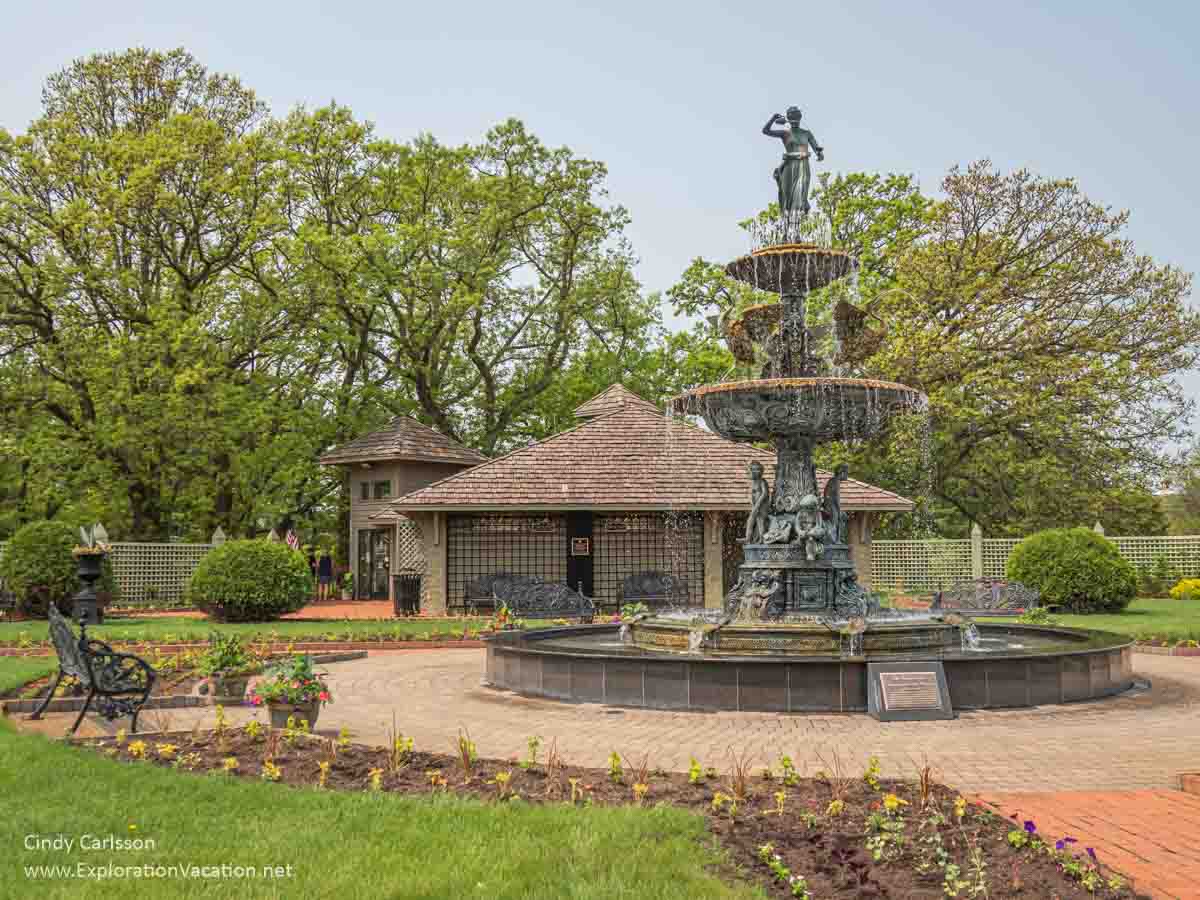 Towering fountain outside a building in a garden.