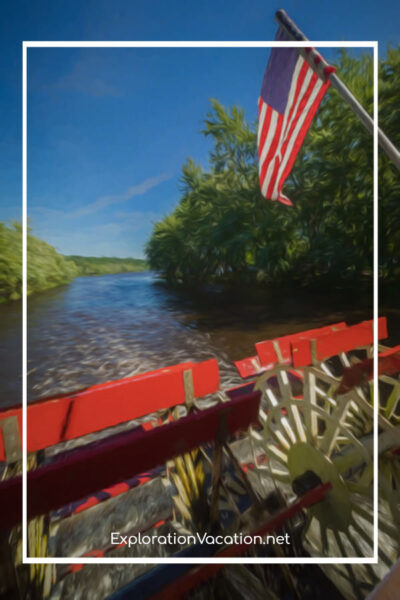 paddlewheel on a boat with river and USA flag