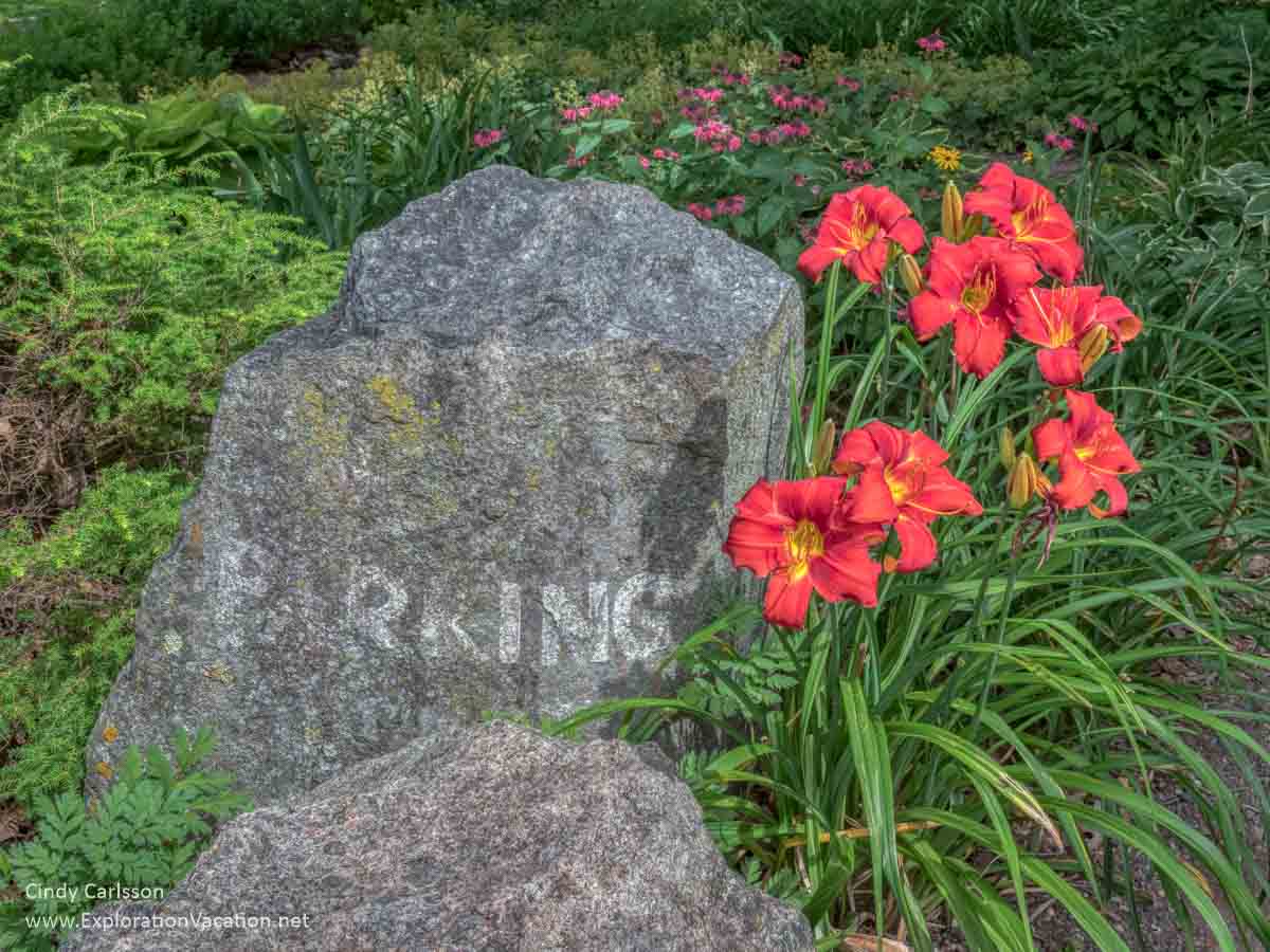 stone that has "parking" carved on it with red/orange day lilies
