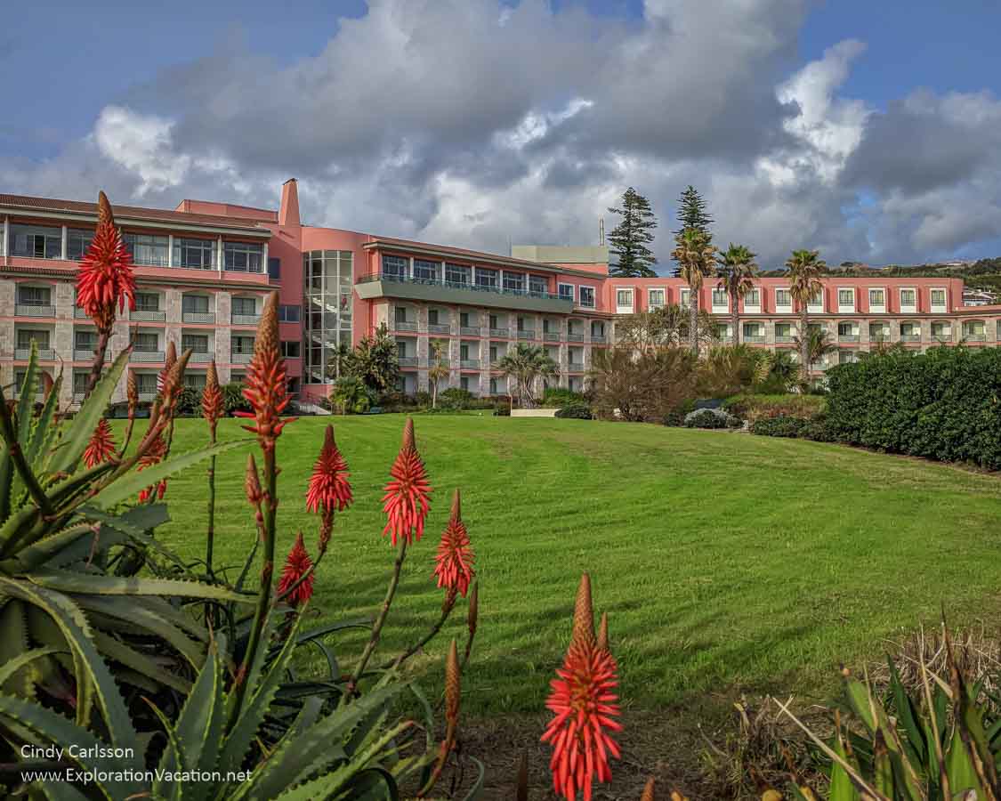 a brightly colored hotel with lawn and large aloes