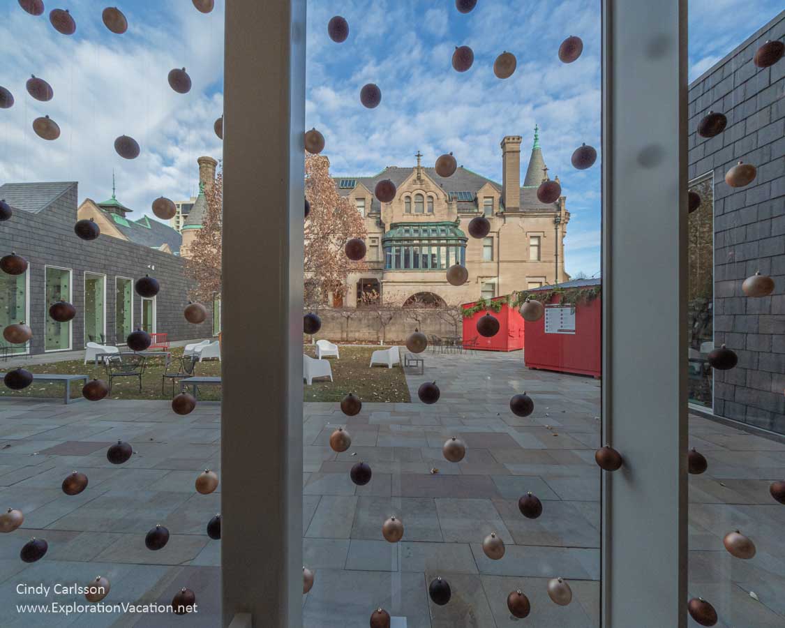 view of a mansion and courtyard through a window with Christmas ornaments 